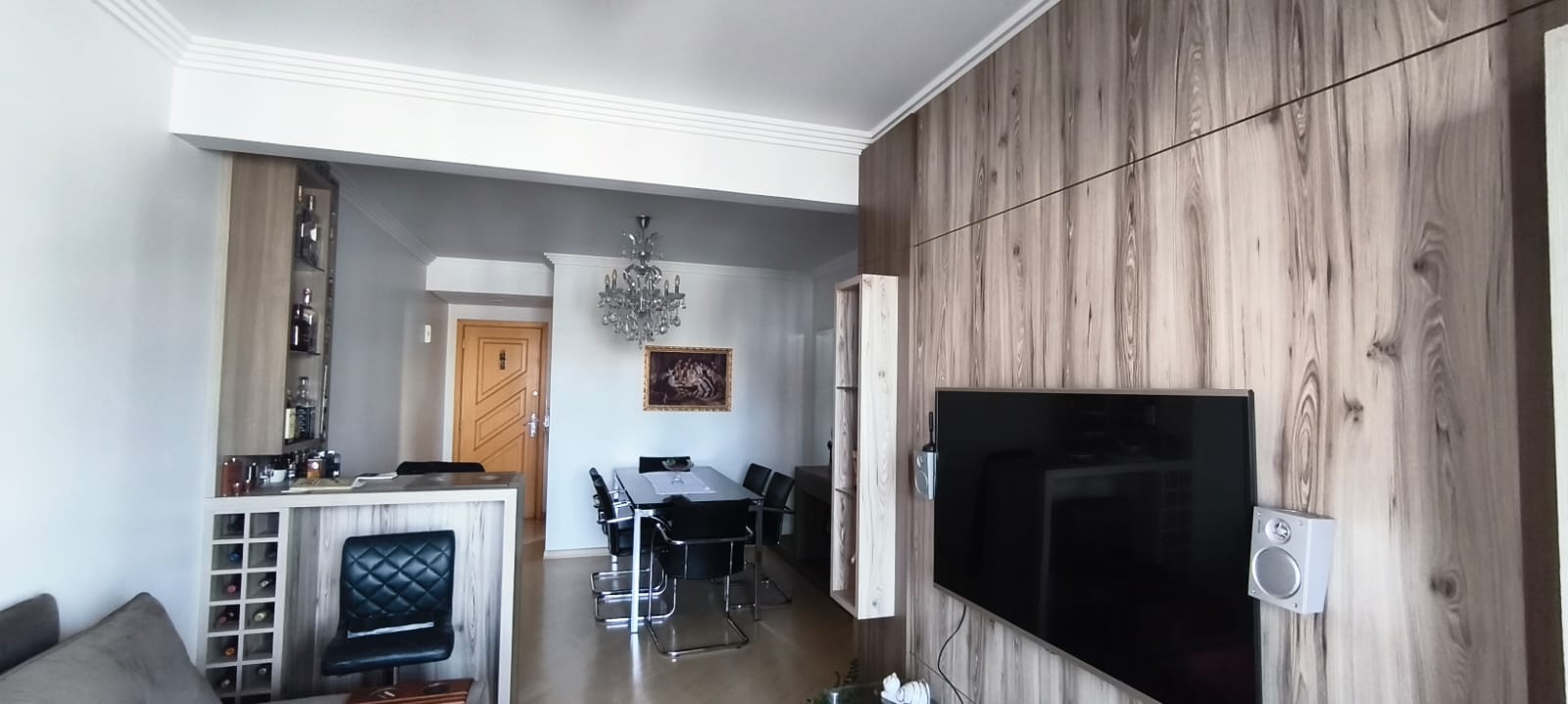Sala de estar integrada com painel de madeira e TV